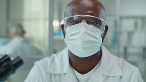 portrait of african american scientist in mask and glasses in lab