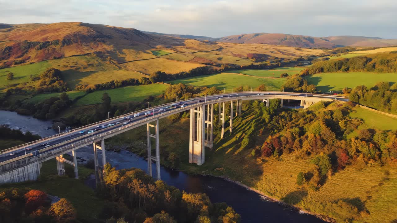 Aerial view of a large bridge with cars over a river in a scenic rural valley