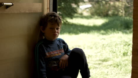 a young boy sitting at the doorway