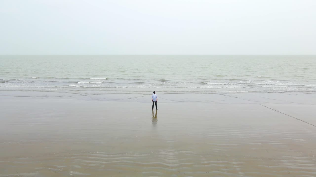 불행한 외로운 남자가 방글라데시의 조용한 해변 앞에서  ⁇ 상하고 있습니다.