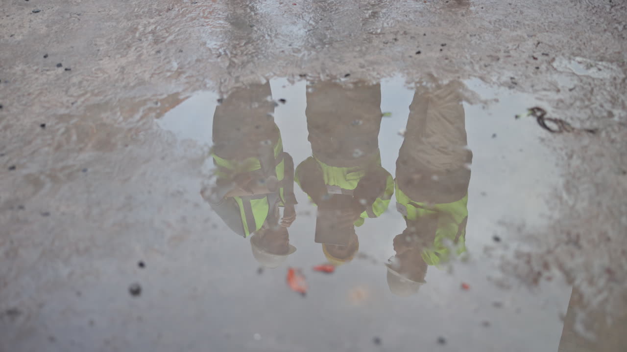 Reflection of construction workers in a puddle