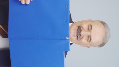 video vertical de un viejo hombre de negocios mirando desde detrás de los archivos.