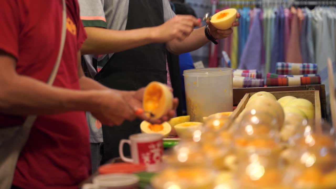 vendedores sacando la carne de melones dulces con una cuchara