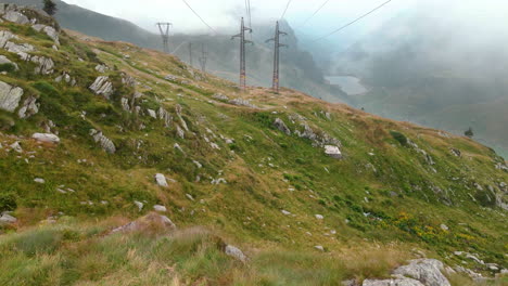 flying over the rocks of the mountain fields near the high voltage cables in passo san marco, northern italy - aerial drone shot