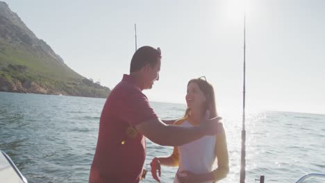 vista lateral de un hombre caucásico y su hija adolescente disfrutando del tiempo en un barco