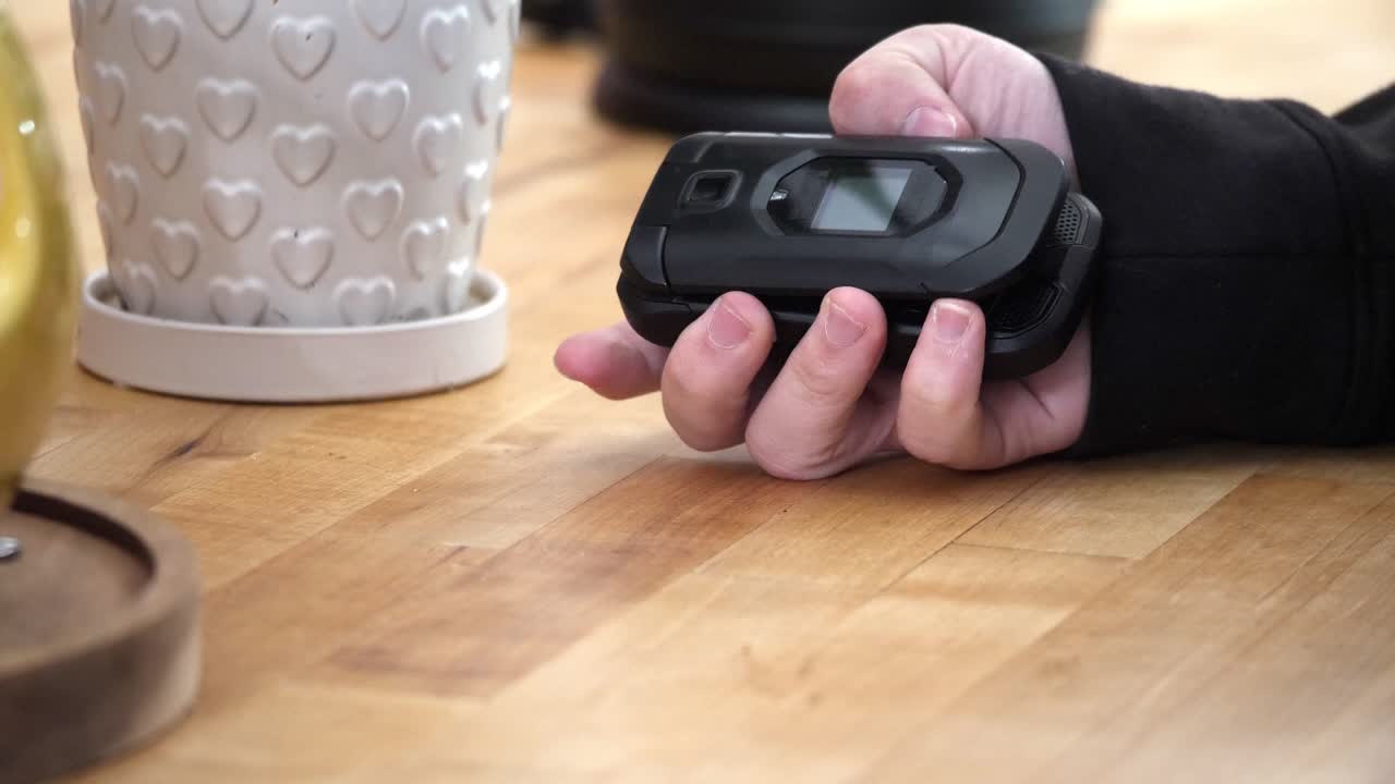 Closeup shot of someone opening a flip phone and pressing a few buttons in slow motion