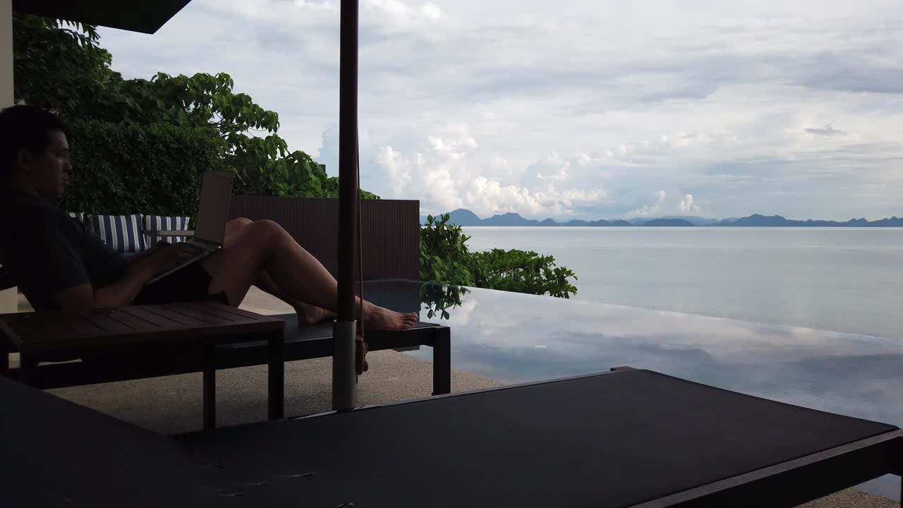 Asian Man Working On The Laptop By The Pool - Back View Free Stock Video  Footage Download Clips