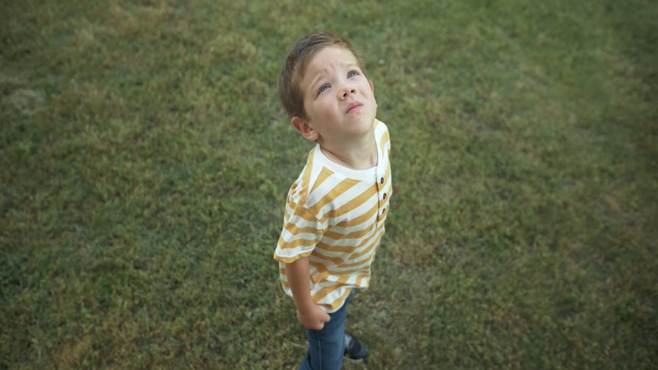 A young boy gazes up at the sky in slow motion, his eyes full of wonder and curiosity. This cinematic footage captures the innocence and imagination of childhood.