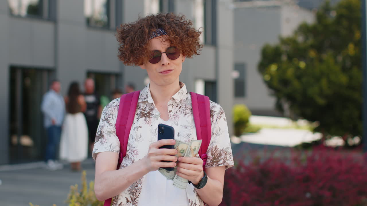 Happy rich tourist man counting holding money dollar cash use smartphone calculator app outdoors