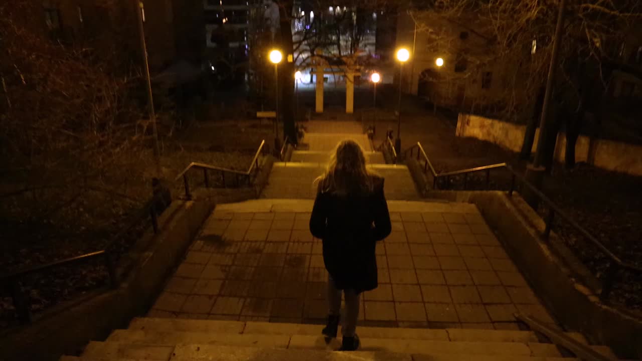 Girl walking down the stairs outside, view from the back