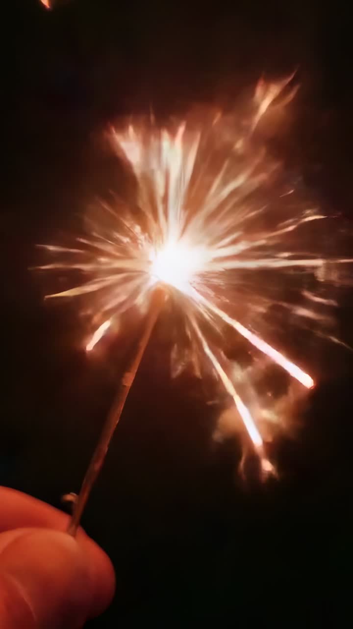 Video verticale: accensione di una scintilla, mano che tiene un bastoncino di metallo che crea scintille luminose nel cielo notturno