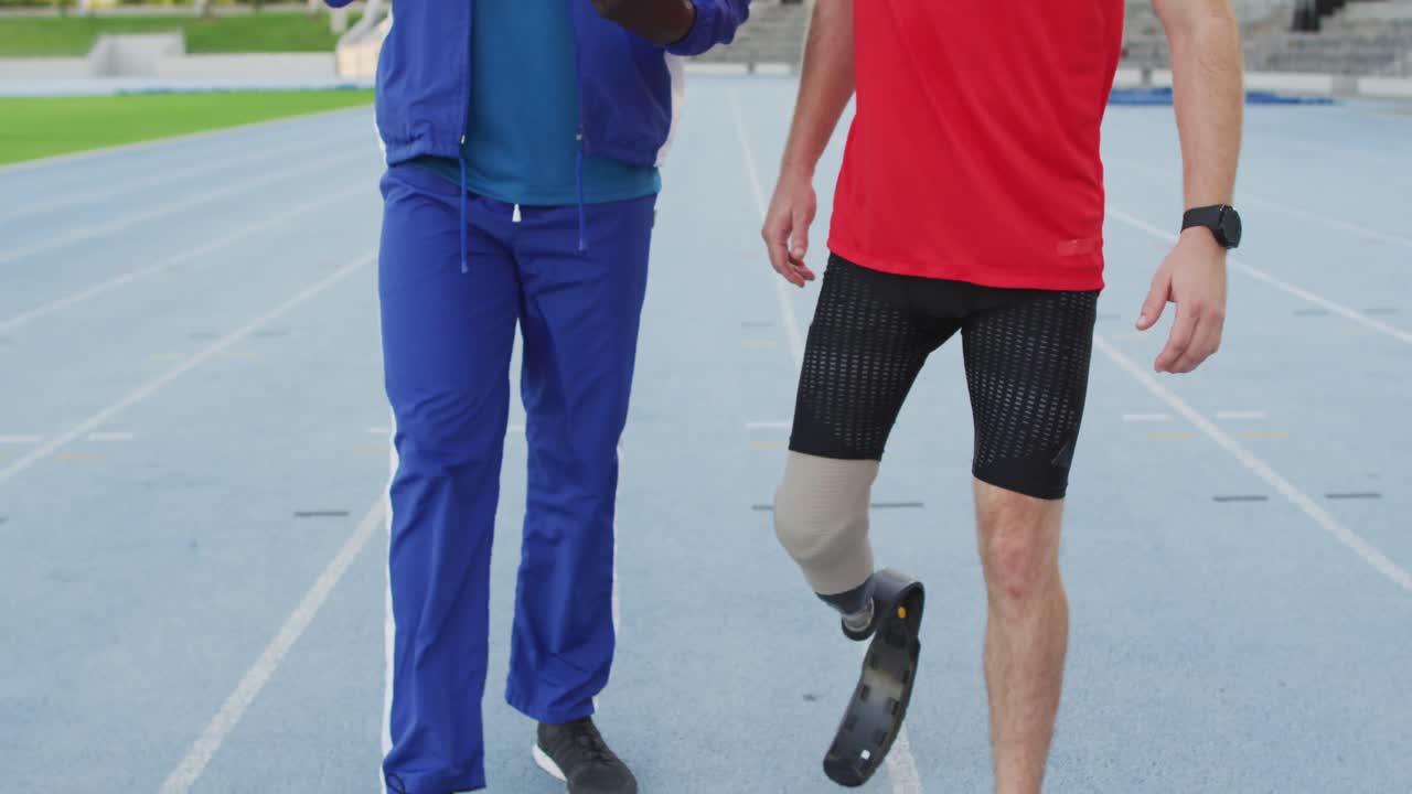 entrenador masculino diverso y atleta discapacitado con cuchilla de correr hablando durante la sesión de entrenamiento