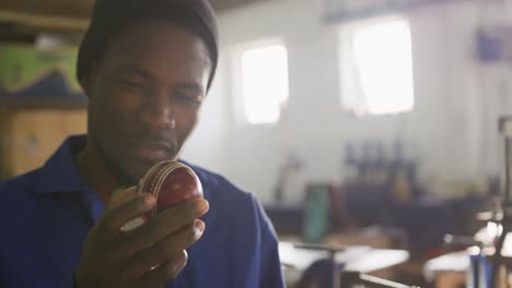 mixed race man holding hand-made ball in factory