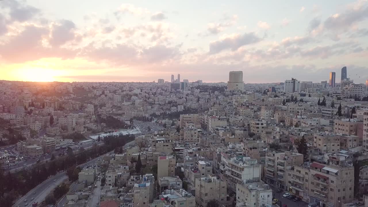 hermoso y pacífico clip aéreo de la madrugada en la ciudad de amman, jordania, tomado por un dron con el horizonte rompiendo en tonos rosados y amarillos de un sol naciente
