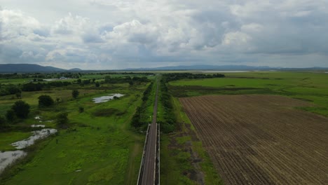 Aerial-footage-taken-during-the-afternoon-towards-the-horizon-revealing-newly-tilled-farmlands,-mountains,-rainclouds