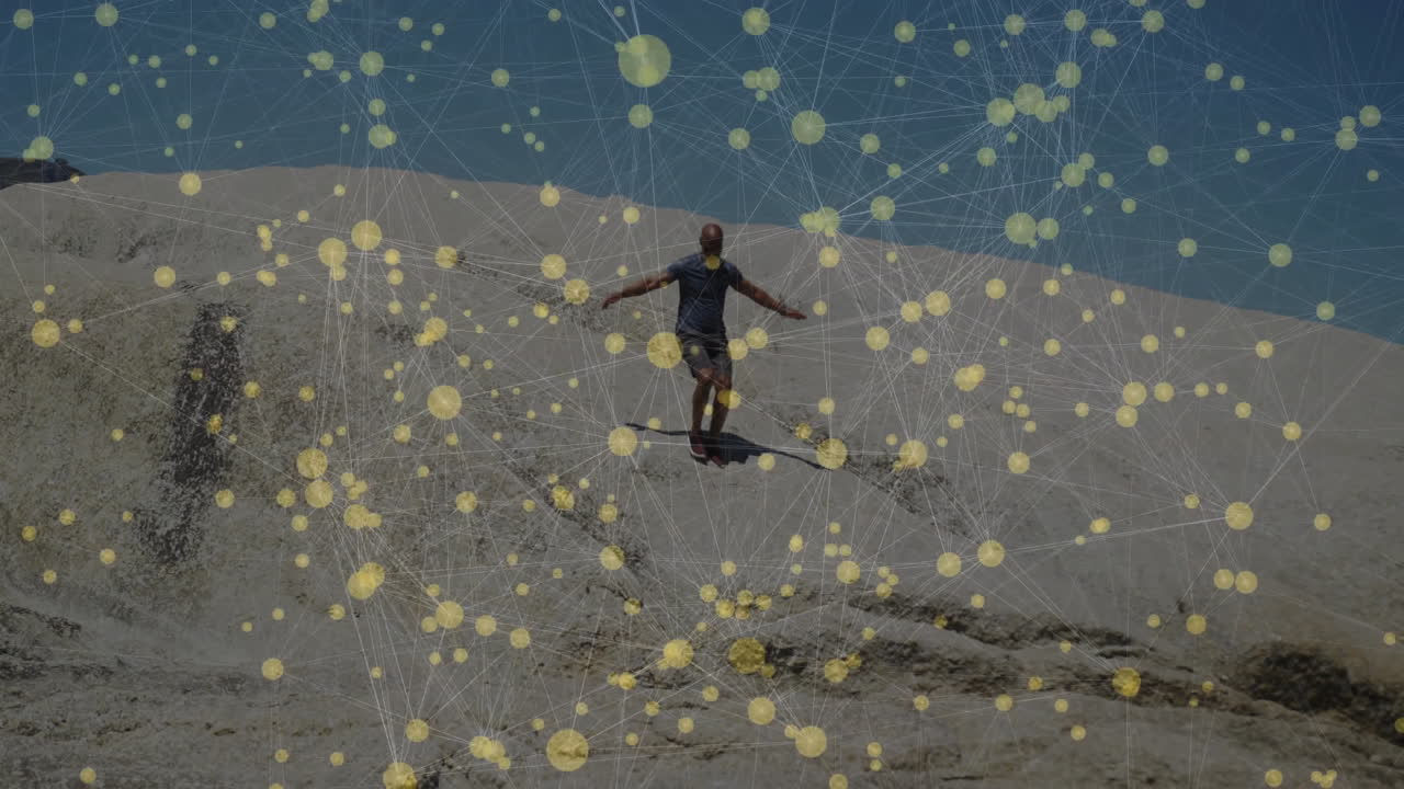 Man jumping down desert dune, showcasing digital network overlay for tech data visualization