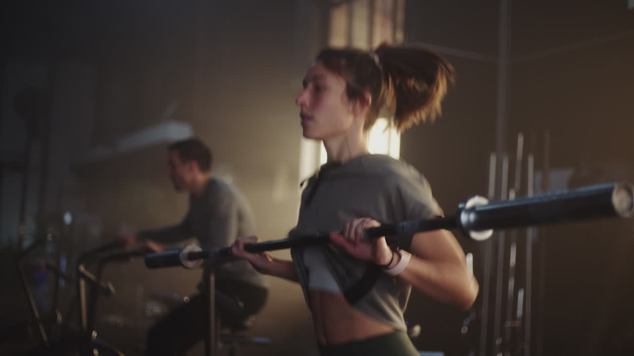 체육관 에서 바벨 을 들고 운동 하는 여자