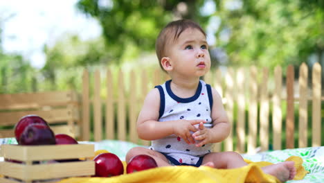 adorable little baby sitting on the plaid in the garden. cute peaceful kid watching the soap bubbles fly down. blurred backdrop.