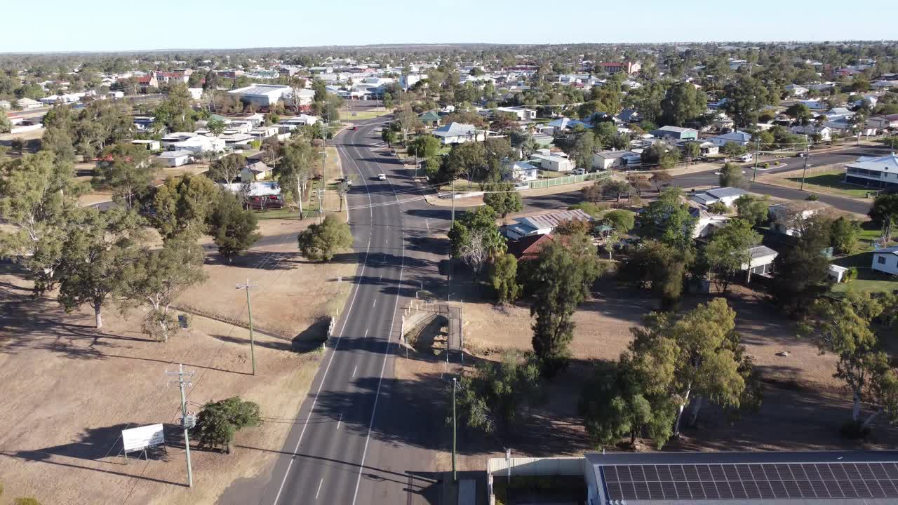 Dron volando sobre un motel con paneles solares en el tejado y una carretera en un pequeño pueblo de Australia.