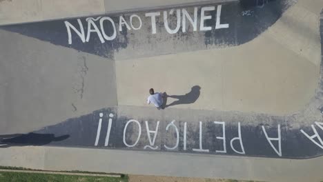 aerial view of teenager skateboarding at outdoor skate park in a estoril saying "não ao túnel" in pdg, estoril, cascais