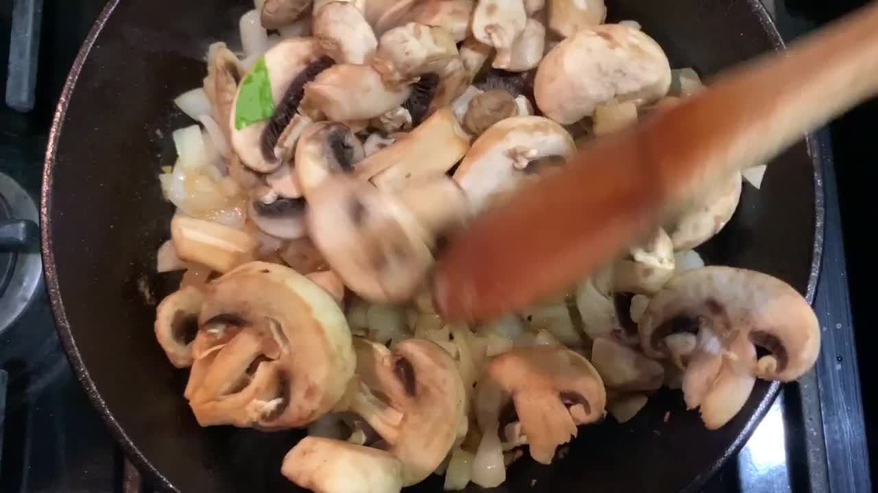 Cooking mushrooms and onions over a cast iron skillet