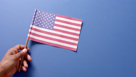 cerca de la mano sosteniendo la bandera nacional de los estados unidos sobre un fondo azul