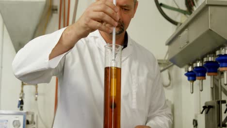 trabajador masculino examinando el licor en el cilindro de medición 4k