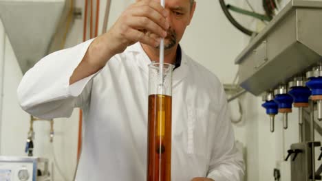 male worker examining liquor in measuring cylinder 4k