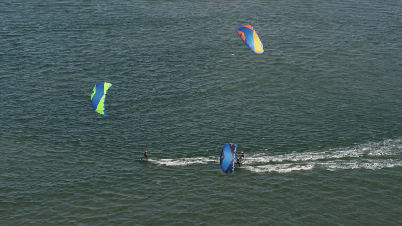 tres kiters haciendo kitesurf en el océano azul