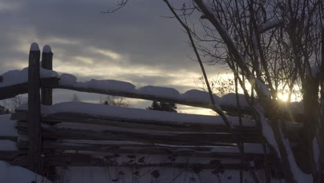 Rustic-Farm-Fence-Covered-In-Snow-At-Sunrise,-Cold-Cloudy-Landscape