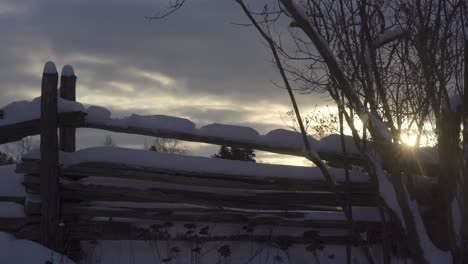 valla de granja rústica cubierta de nieve al amanecer, paisaje frío y nublado