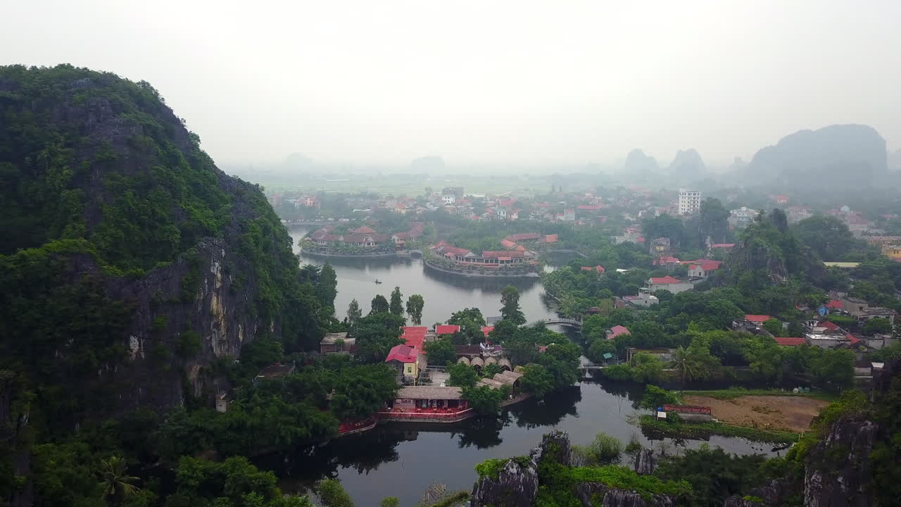 Experience the atmospheric beauty of Ninh Binh city, Vietnam, on a cloudy and rainy day. This view captures the misty landscapes and serene urban settings amidst the region's iconic karst formations.