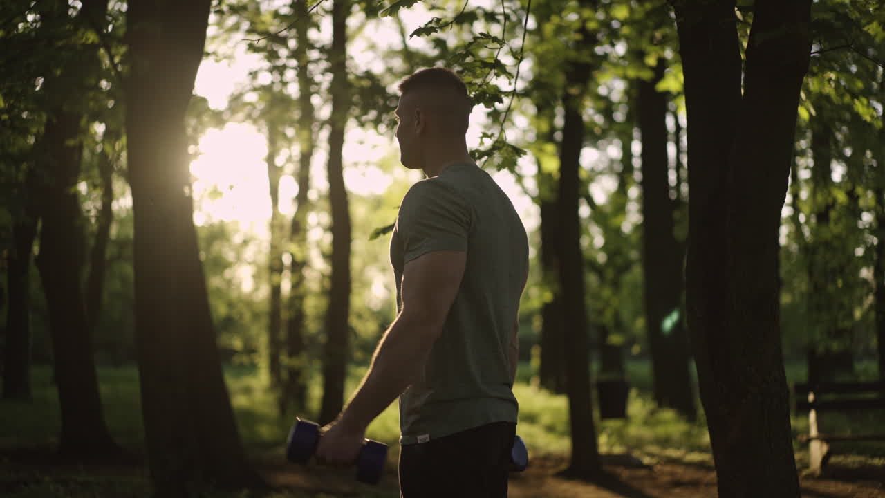 Man exercising with dumbbells in a forest