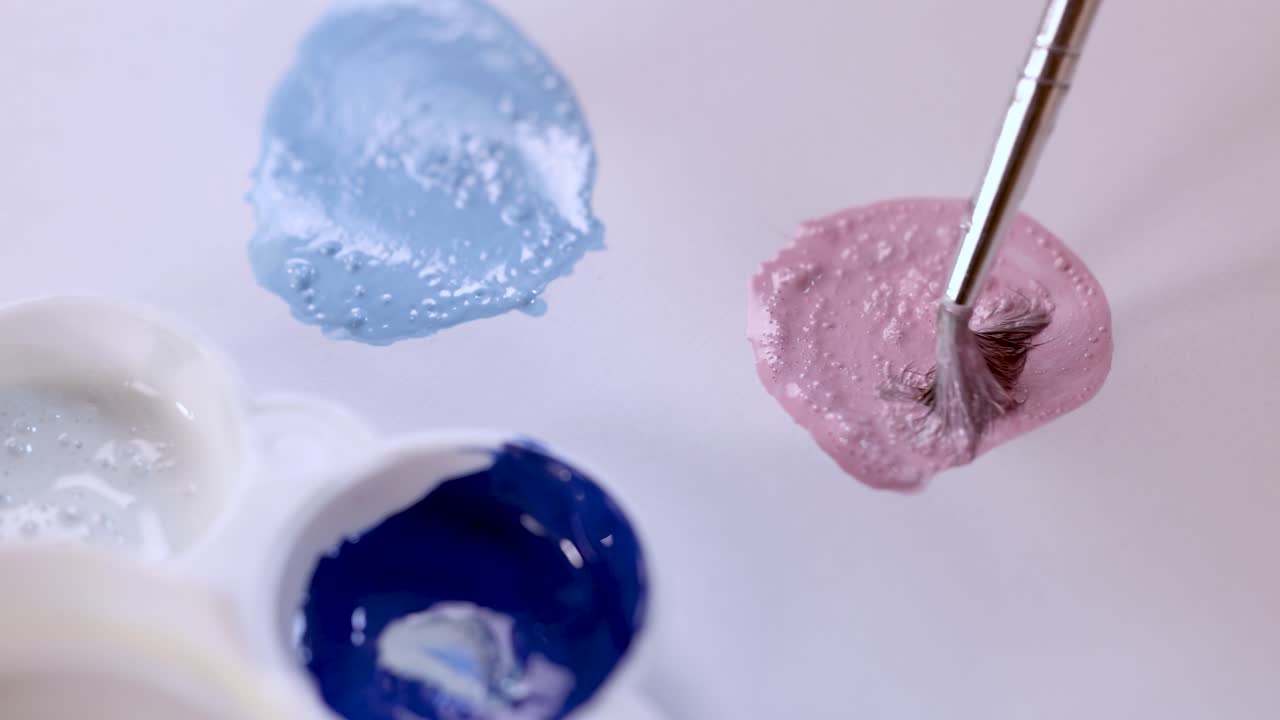 Artist mixes pink paint with brush on palette, close-up, soft lighting, smooth camera movement