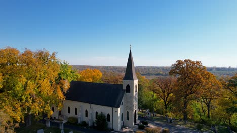 alte kirche und friedhof in bunter herbstwalddrohne