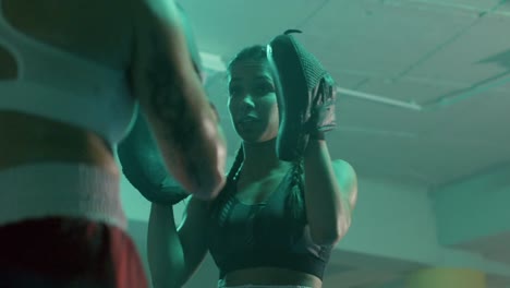 dos boxeadoras caucásicas entrenando juntas en un gimnasio de boxeo