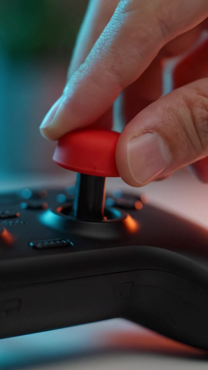 A close-up view of a gaming controller's joystick showcasing a vibrant red cap contrasting with black body, highlighting the details of gaming accessories and style.