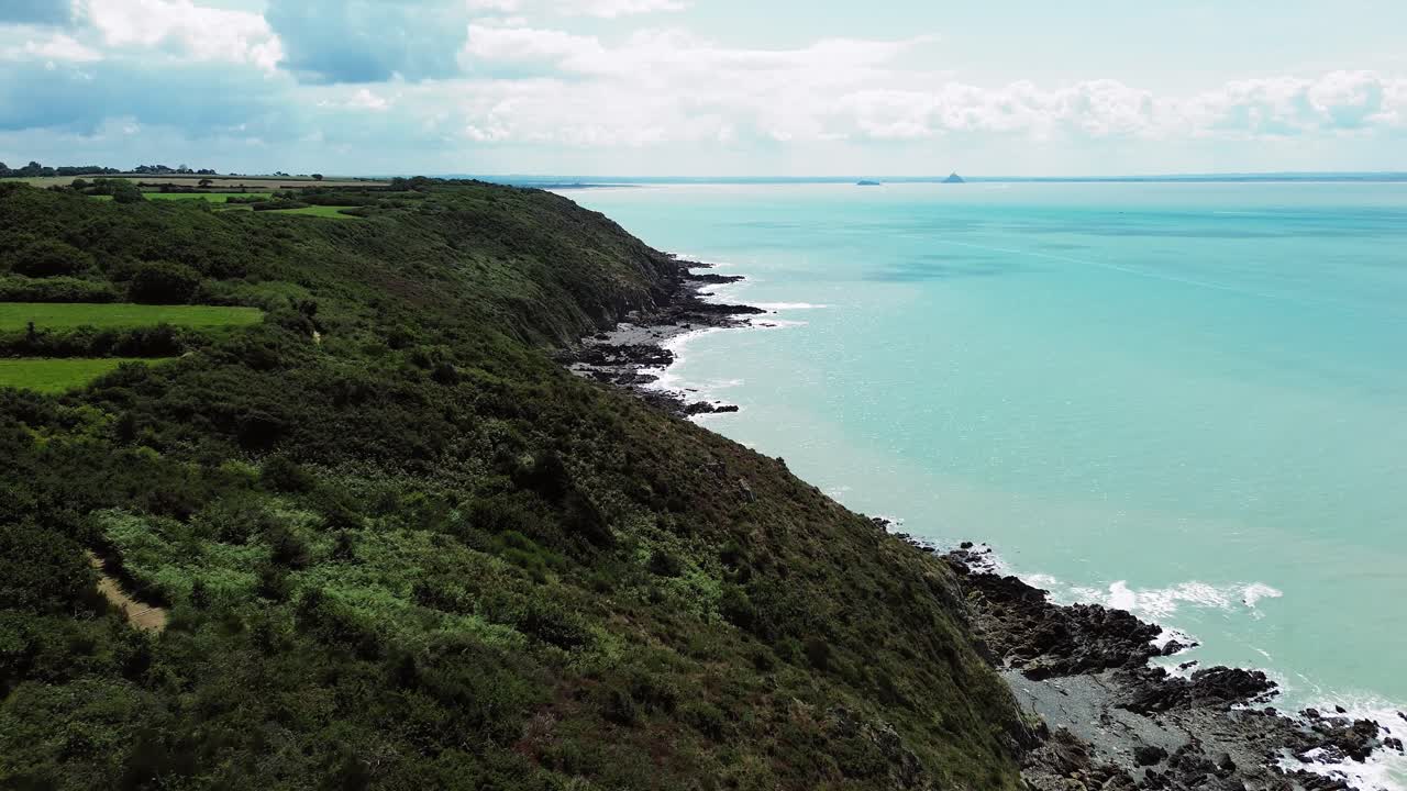 Aerial drone footage reveals the stunning cliffs of Carolles, with the small stone Cabane Vauban standing guard above the waves