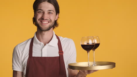 caucasian waiter in front of camera on yellow background.