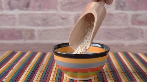 wooden scoop pouring oatmeal into bowl