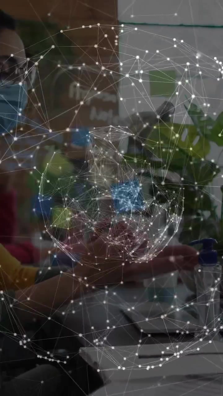 Vertical video: Masked man sanitizing after typing for hygiene, IT network globe rotating over desk
