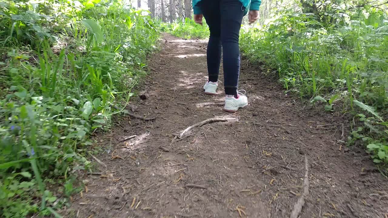 여름에 산을 하이킹하는 동안 스포츠 정장을 입고 숲길을 걷는 여자