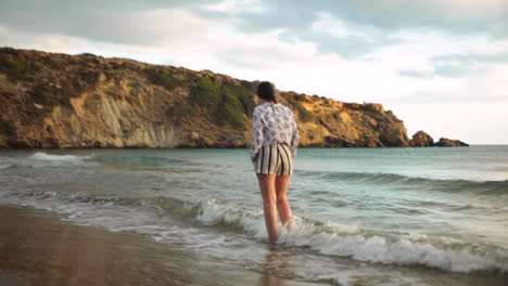 brunette walking on the beach splashed by a wave.