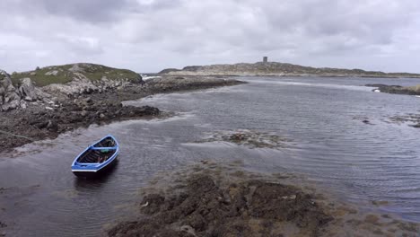 vista aérea del paisaje marítimo de marea baja. barco azul en el océano de aguas bajas redondeado de rocas y musgo. punto de vista de drones de la costa irlandesa en marea baja, en el faro de fondo