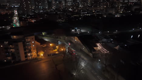 aerial view following a double decker bus driving on the streets of london, night