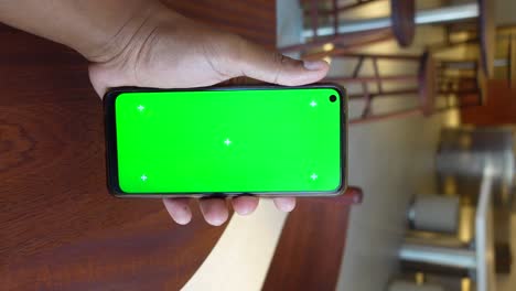 hand holding smartphone with green screen display and tracking markers