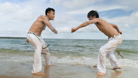 two men dancing capoeira on the beach