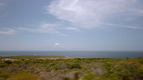 driving through cape of new hope point of view inside car agricultural fields of south african countryside, skyline and ocean background in sunny daylight