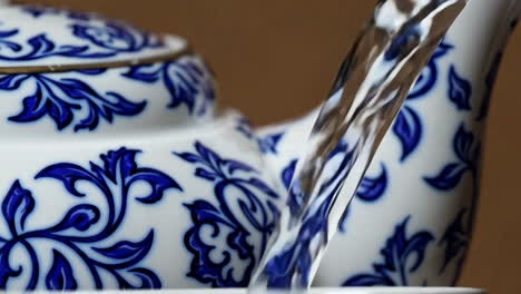 pouring water into a decorative blue and white tea kettle