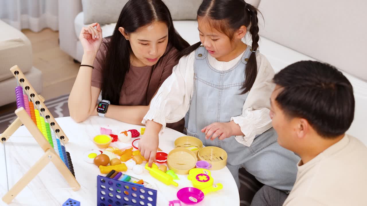 Parents and daughter interact with educational toys in bright living room, natural lighting, overhead view